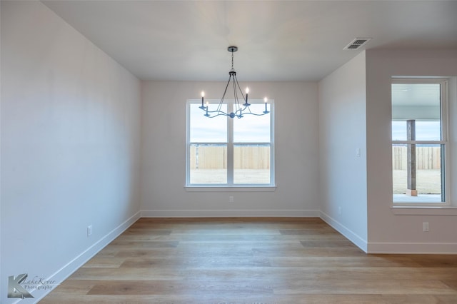 unfurnished dining area featuring a notable chandelier and light hardwood / wood-style flooring