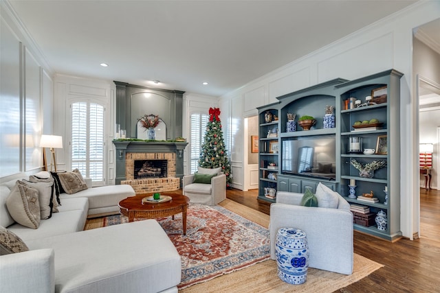 living room featuring crown molding, a fireplace, wood-type flooring, and built in features