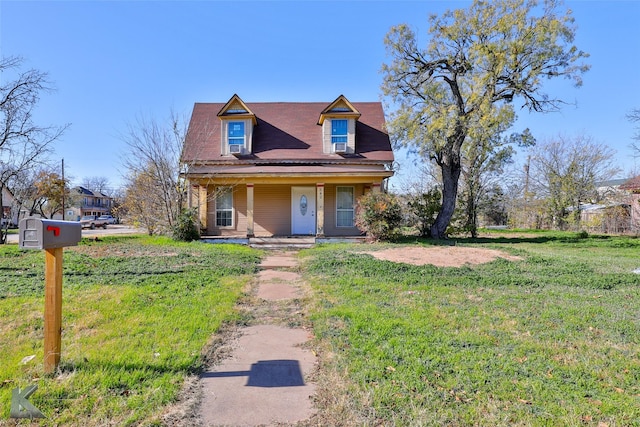 cape cod home with covered porch and a front lawn