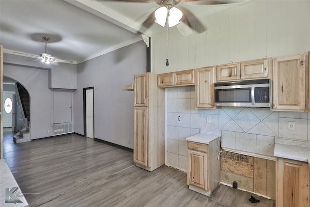 kitchen with hardwood / wood-style flooring, ceiling fan, light brown cabinets, and backsplash