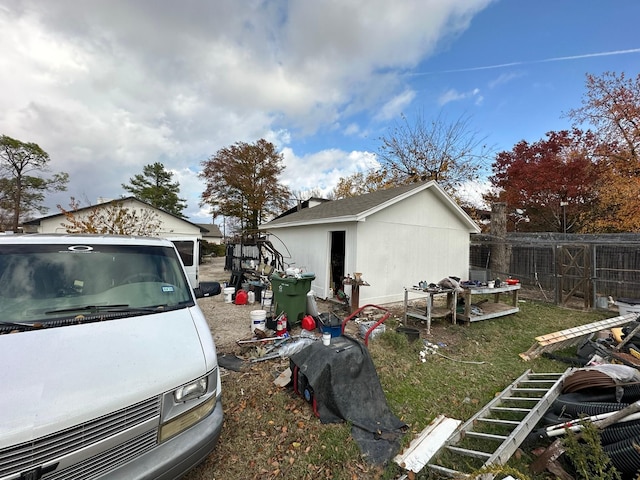 view of side of home with a lawn, an outdoor structure, and fence