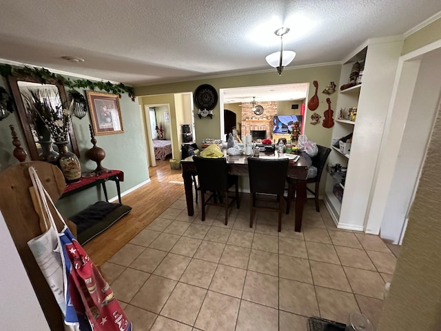 dining room featuring a textured ceiling, a brick fireplace, and crown molding