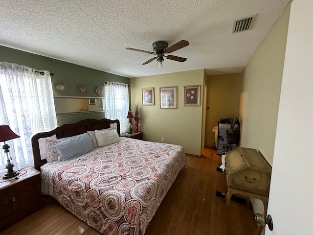 bedroom featuring visible vents, ceiling fan, a textured ceiling, and wood finished floors