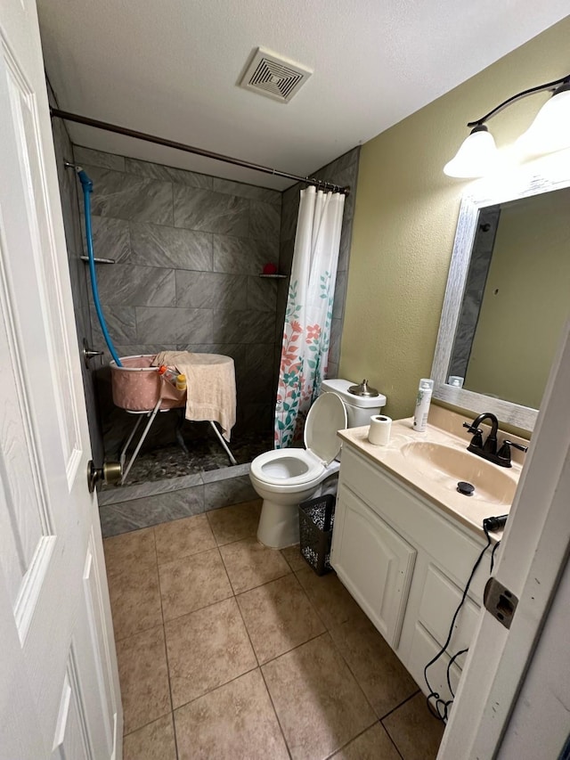 full bath with visible vents, toilet, a tile shower, vanity, and a textured ceiling