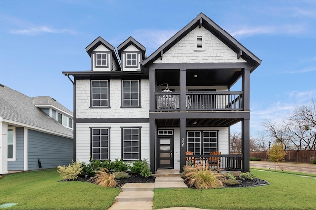 view of front of house with covered porch, a balcony, and a front lawn