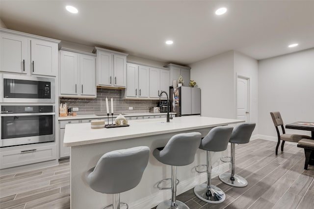 kitchen featuring a center island with sink, white cabinetry, and stainless steel appliances