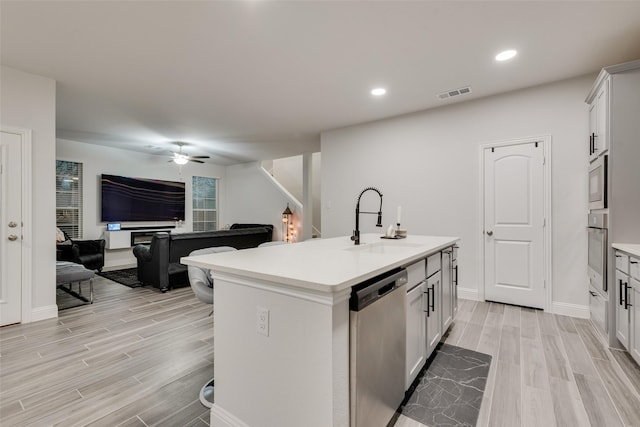 kitchen with appliances with stainless steel finishes, white cabinetry, a kitchen island with sink, and sink