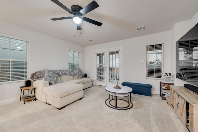 carpeted living room with ceiling fan and french doors