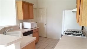 kitchen with kitchen peninsula, sink, light tile patterned floors, and exhaust hood