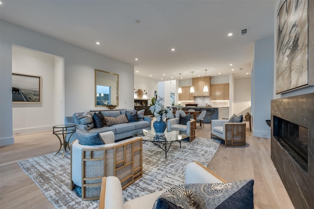 living room featuring a high end fireplace and light wood-type flooring