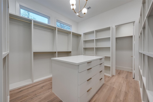 walk in closet featuring light hardwood / wood-style flooring and an inviting chandelier