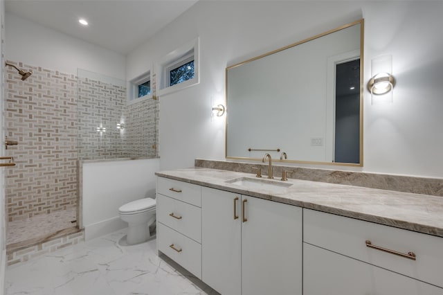 bathroom with a tile shower, vanity, and toilet