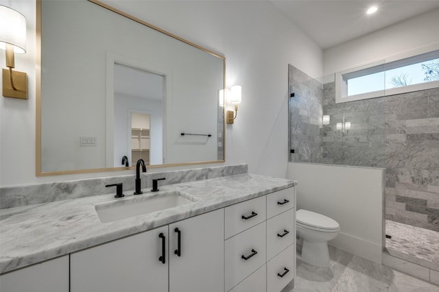 bathroom with a tile shower, vanity, and toilet