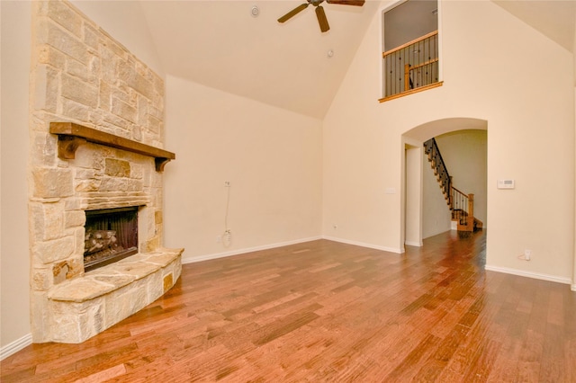 unfurnished living room featuring hardwood / wood-style flooring, ceiling fan, a fireplace, and high vaulted ceiling