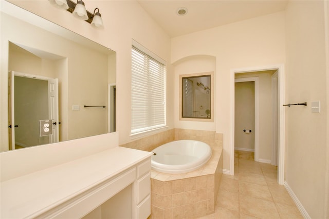 bathroom with tile patterned floors, tiled bath, and vanity