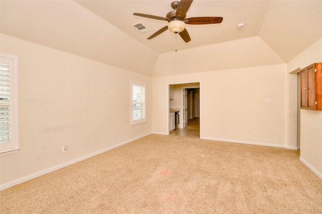 empty room featuring ceiling fan, lofted ceiling, and light carpet