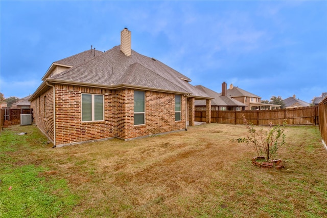 rear view of property with central AC and a lawn