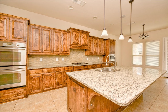 kitchen with a kitchen bar, appliances with stainless steel finishes, a kitchen island with sink, decorative light fixtures, and an inviting chandelier