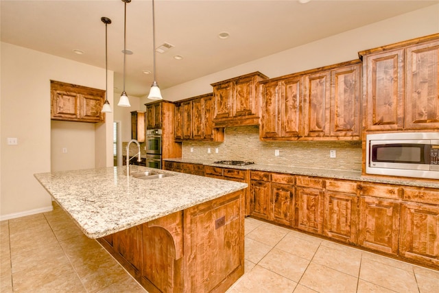 kitchen featuring sink, an island with sink, pendant lighting, decorative backsplash, and appliances with stainless steel finishes