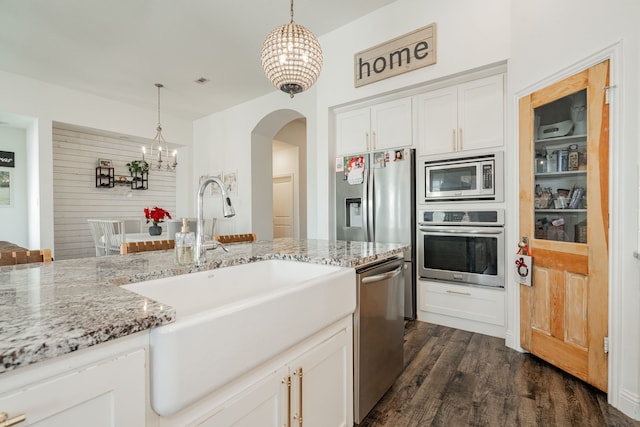 kitchen with an inviting chandelier, sink, appliances with stainless steel finishes, decorative light fixtures, and white cabinetry