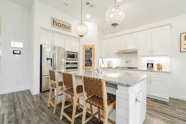 kitchen featuring stainless steel appliances, white cabinetry, hanging light fixtures, and an island with sink