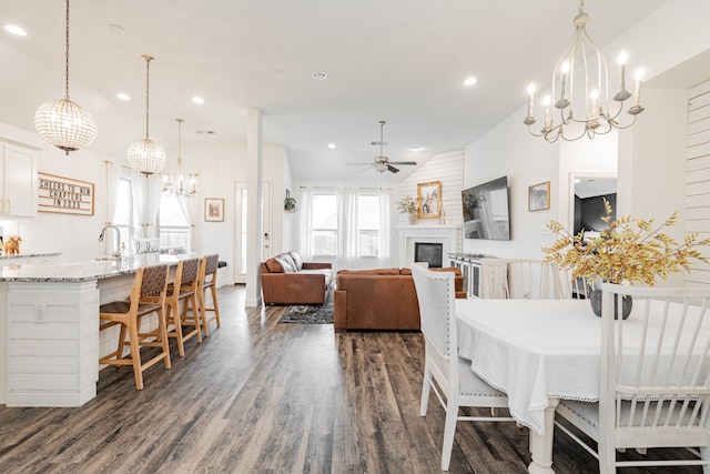 dining room with sink, lofted ceiling, dark hardwood / wood-style flooring, and ceiling fan with notable chandelier