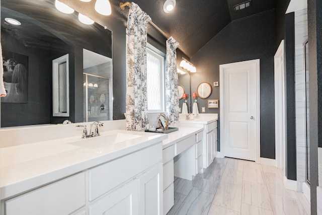 bathroom featuring vanity, a shower with door, and vaulted ceiling