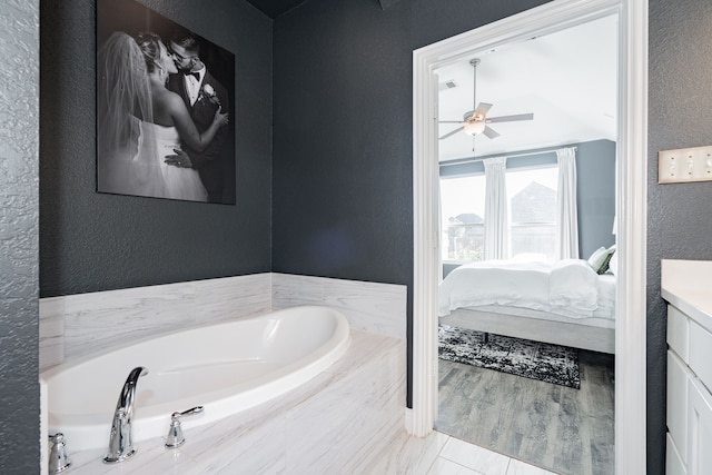 bathroom with vanity, a relaxing tiled tub, and ceiling fan