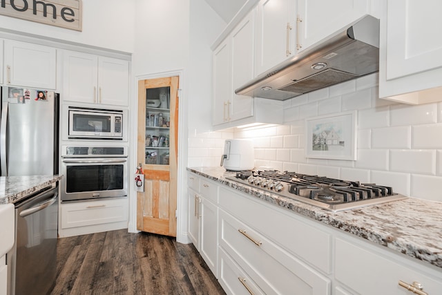 kitchen featuring light stone counters, white cabinetry, stainless steel appliances, and dark hardwood / wood-style floors