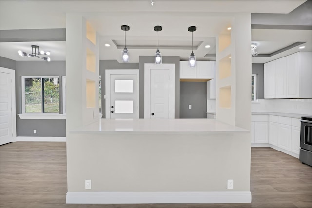 kitchen featuring white cabinets, a notable chandelier, light wood-type flooring, and decorative light fixtures