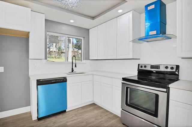 kitchen featuring appliances with stainless steel finishes, light wood-type flooring, sink, wall chimney range hood, and white cabinetry