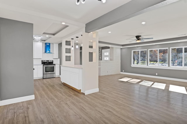 unfurnished living room with ceiling fan, a raised ceiling, and light wood-type flooring