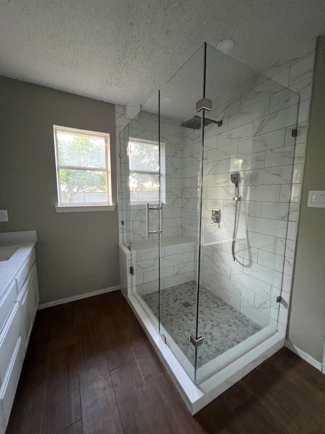 bathroom featuring vanity, wood-type flooring, a shower with door, and a textured ceiling