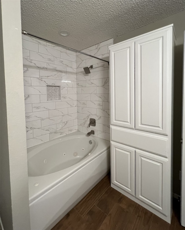 bathroom featuring a textured ceiling, hardwood / wood-style floors, and tiled shower / bath combo