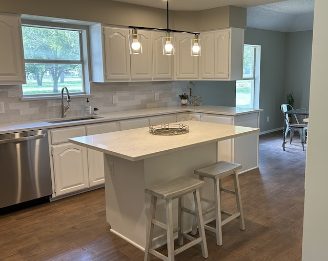 kitchen featuring sink, hanging light fixtures, white cabinets, a kitchen island, and stainless steel dishwasher