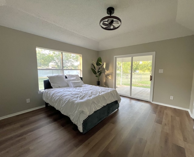 bedroom with a textured ceiling, access to exterior, and dark wood-type flooring