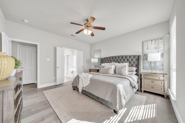 bedroom with light hardwood / wood-style floors, ensuite bath, and ceiling fan