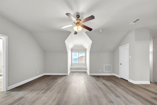 bonus room featuring a textured ceiling, ceiling fan, light hardwood / wood-style flooring, and vaulted ceiling