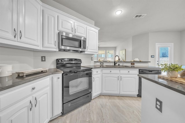 kitchen with kitchen peninsula, white cabinetry, sink, and appliances with stainless steel finishes