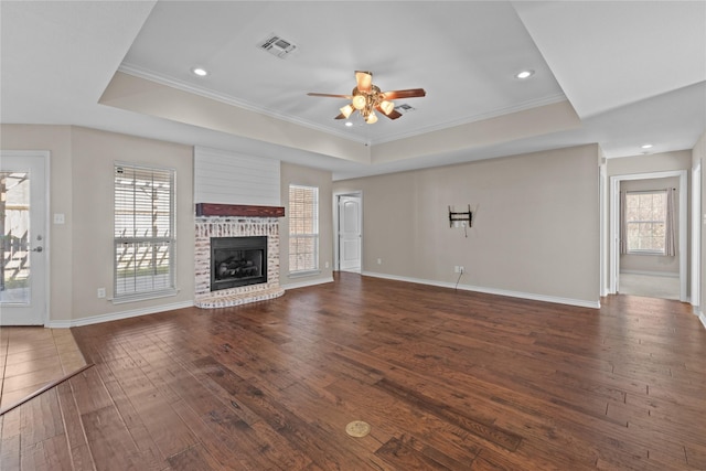 unfurnished living room with a wealth of natural light, ceiling fan, dark hardwood / wood-style floors, and a brick fireplace