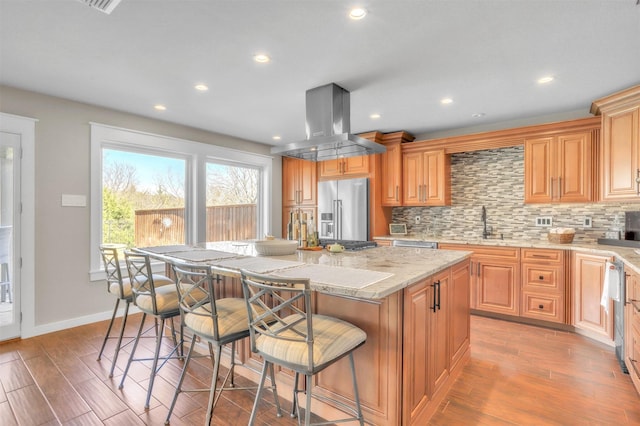 kitchen featuring a kitchen island, island exhaust hood, appliances with stainless steel finishes, and decorative backsplash