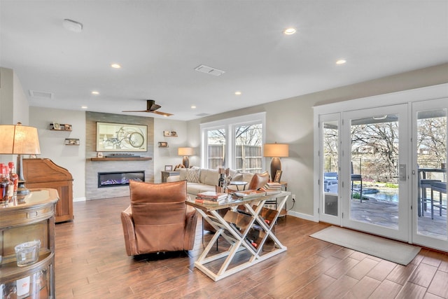 living room with a large fireplace, hardwood / wood-style floors, and ceiling fan