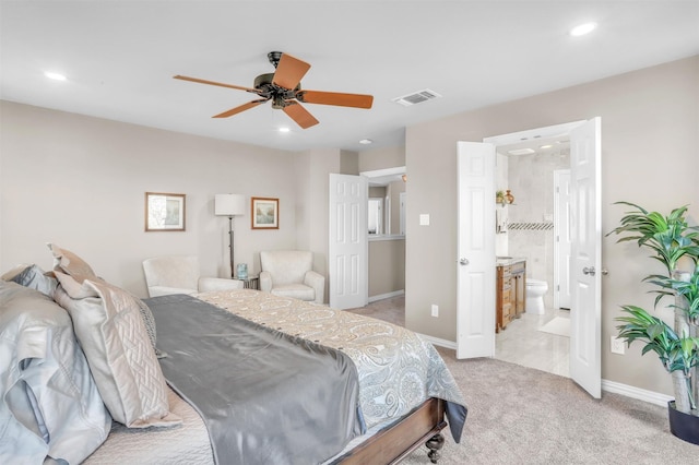 bedroom featuring light carpet, ceiling fan, and ensuite bathroom