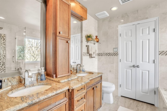 bathroom with vanity, toilet, a shower with shower door, and tile walls