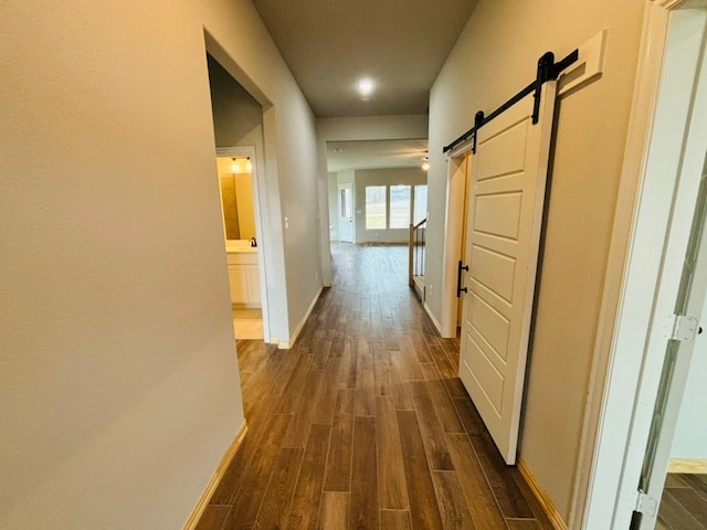 hall with a barn door and dark hardwood / wood-style flooring