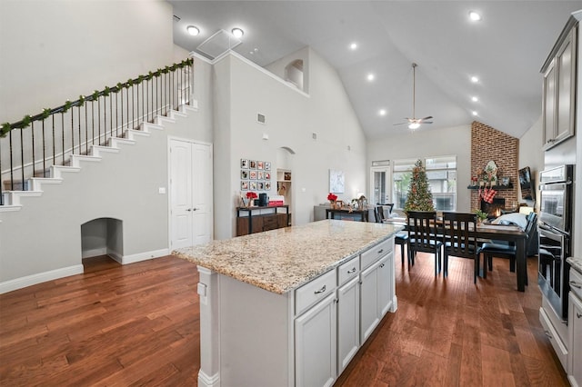 kitchen featuring light stone countertops, dark hardwood / wood-style flooring, a center island, and ceiling fan