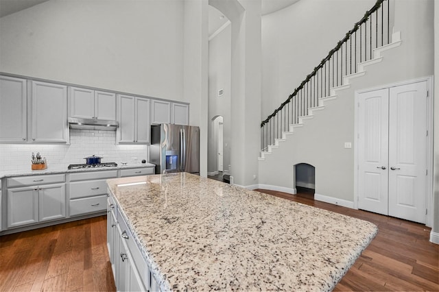 kitchen featuring light stone counters, a center island, a high ceiling, and appliances with stainless steel finishes