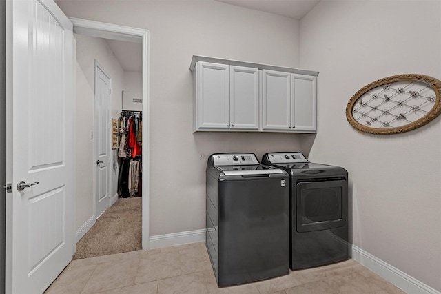 clothes washing area featuring light colored carpet, cabinets, and separate washer and dryer