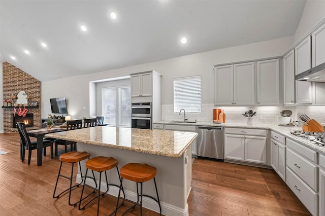 kitchen with a center island, sink, vaulted ceiling, dark hardwood / wood-style floors, and stainless steel appliances