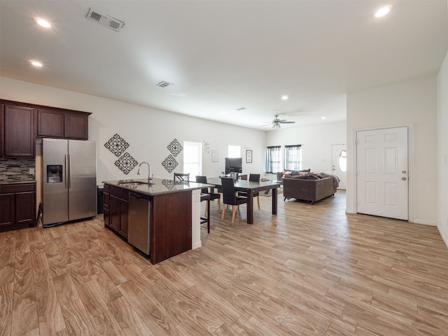 kitchen with sink, light wood-type flooring, an island with sink, appliances with stainless steel finishes, and dark brown cabinets